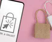 Click&Collect symbol auf Smartphone und Einkaufstüten vor rosa Hintergrund