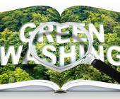 aufgeschlagenes Buch mit Green Washing Schriftzug unter Lupe