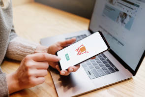 Frau kauft mit Laptop und Smartphone online ein 